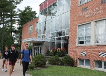 Students walk along the path in front of a brick building on Concord University's campus
