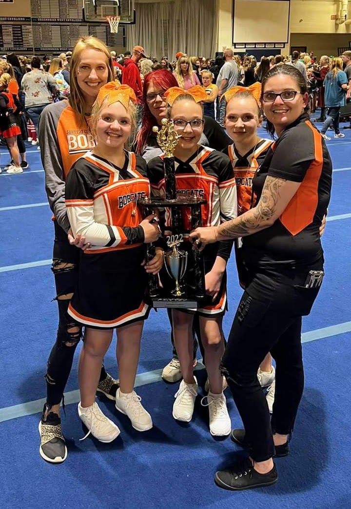 The A Team Cheerleaders and their coaches hold their trophy