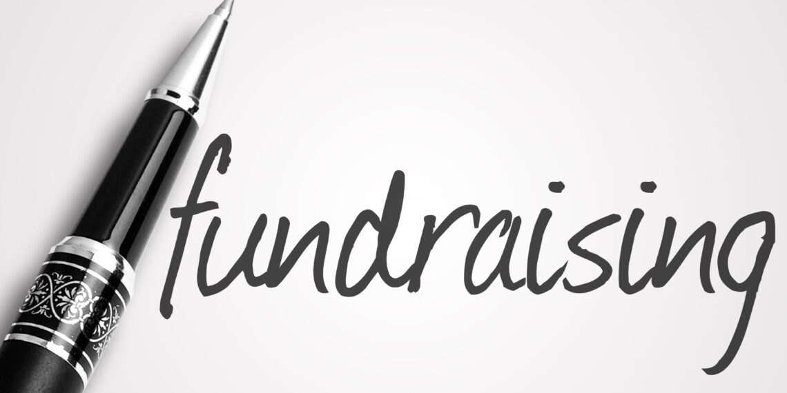 pen writes fundraising on white blank paper.