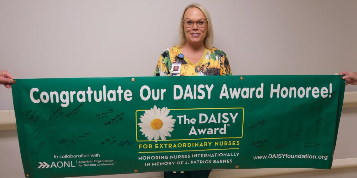 Julie Prinzbach, RN, with the WVU Medicine PCH DAISY banner. 
