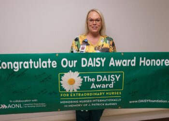 Julie Prinzbach, RN, with the WVU Medicine PCH DAISY banner. 