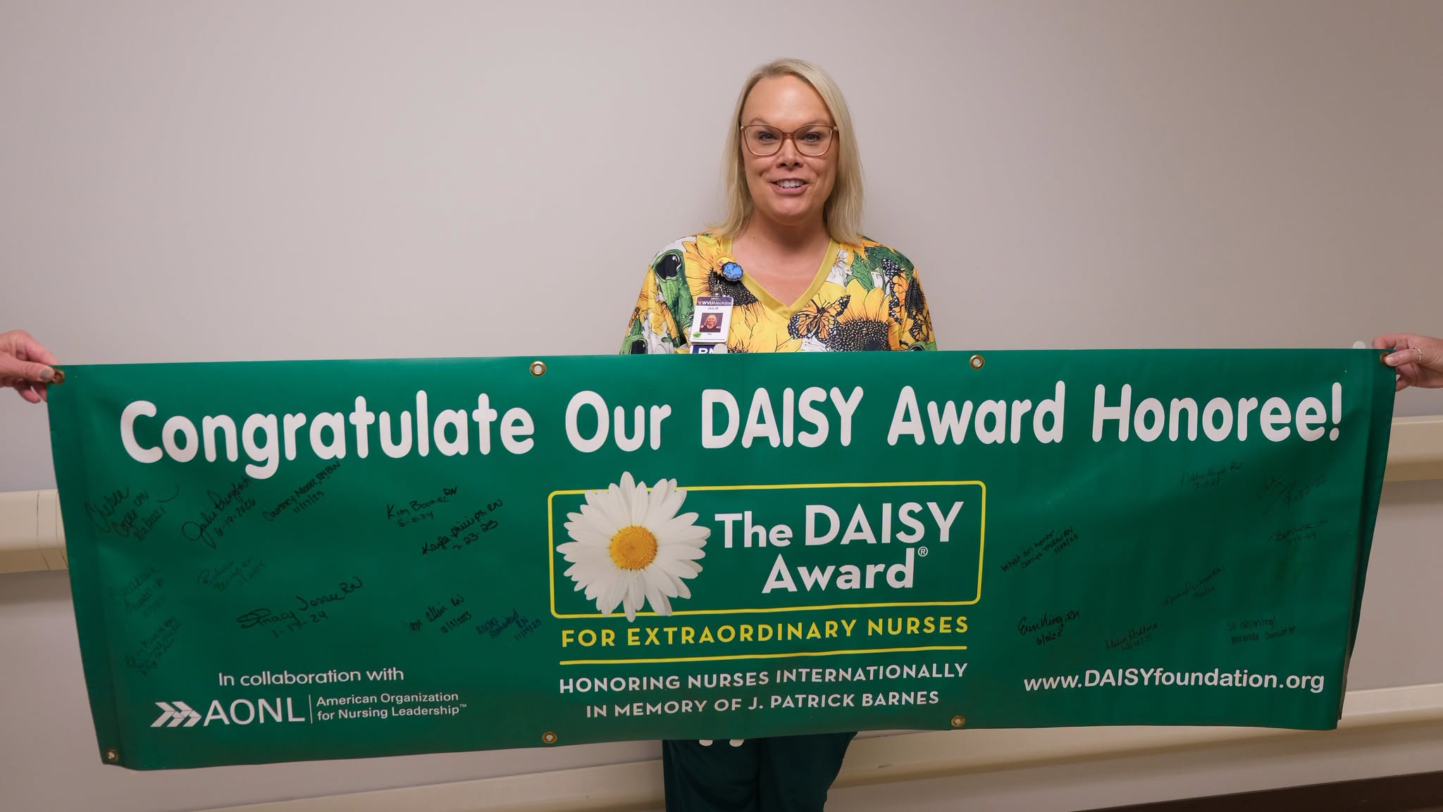 Julie Prinzbach, RN, with the WVU Medicine PCH DAISY banner. 